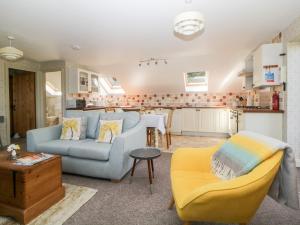 a living room with a blue couch and a kitchen at The Hayloft in Lostwithiel