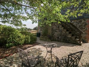 a patio with two chairs and a table and a staircase at The Hayloft in Lostwithiel