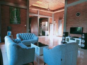 a living room with two blue couches and a tv at Villa Forest Puncak in Tagalbato