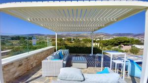 a white pergola with chairs and tables on a patio at Villa Laguna Blu in Kampos Paros