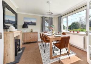 a dining room with a table and chairs and a fireplace at Glenside in Llanbedrog