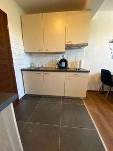 a kitchen with white cabinets and a tile floor at Studio apartman Mia in Tar