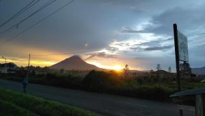 a mountain at sunset with a person walking down a road at Vulkaan Homestay in Berastagi