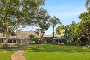 a garden with palm trees and a building at Park Hotel Mokopane in Mokopane