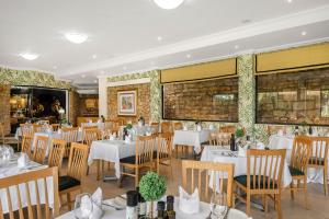 une salle à manger avec des tables et des chaises blanches dans l'établissement Park Hotel Mokopane, à Potgietersrus