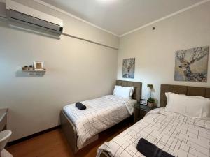 - 2 lits dans une petite chambre aux murs blancs dans l'établissement Cottonwood Apartment at Marbella Suites Dago, à Bandung