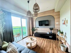 - un salon avec un canapé bleu et une grande fenêtre dans l'établissement Cottonwood Apartment at Marbella Suites Dago, à Bandung