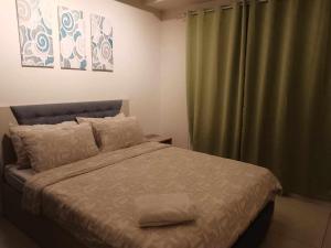 1 dormitorio con 1 cama y cortina verde en Wind Residence T4-R Near Tourist Spots/ Sky Lounge, en Tagaytay