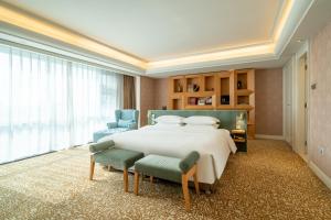 a large bedroom with a large bed and two chairs at Ramada Plaza Taian in Tai'an