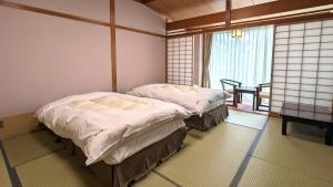 2 camas individuales en una habitación con ventana en Tonamino Shogawaso Ichimantei, en Tonami