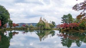 un lago con árboles y un edificio en el medio en Tonamino Shogawaso Ichimantei, en Tonami