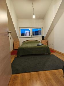1 dormitorio con 1 cama con manta verde y ventana en Chambre privé dans belle maison 2 en Ettelbruck