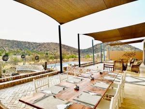 een grote eetkamer met tafels en stoelen op een patio bij Lodge Damaraland in Khorixas