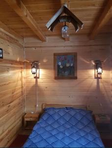 1 dormitorio con 1 cama azul en una cabaña de madera en Domek w Dolinie Bałtów, en Bałtów