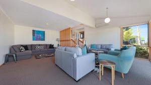 a living room with blue chairs and a couch at Oyster View in Merimbula