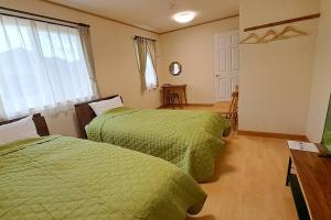 2 Betten in einem Zimmer mit grünen Bettdecken in der Unterkunft ホリデーハウス慈野(ジノ) in Takayama
