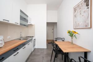 a kitchen with white cabinets and a wooden table at A.S. Home Świdnicka Street in Wrocław