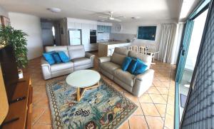a living room with couches and a table and a kitchen at The Norfolks on Moffat Beach in Caloundra