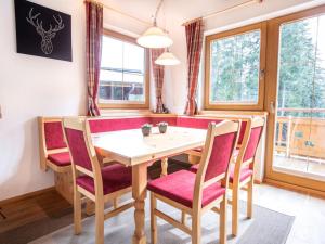 a dining room with a wooden table and red chairs at Chalet Hochkrimml with sauna on the ski slope in Nothdorf