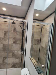 a shower in a bathroom with a glass door at JJs Lodge Oaktree in Thornton