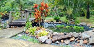 a garden with a pond and a wooden bridge at Najjamee Bungalows in Ko Yao Noi