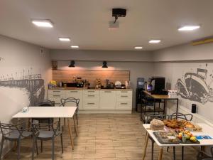 kuchnia z białymi stołami i krzesłami oraz blatem w obiekcie Guest Apartments Orłowo w mieście Gdynia