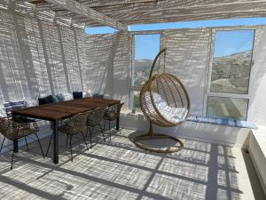 a dining room with a wooden table and chairs at VIlla Gorgona, maison cycladique in Gavrio