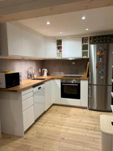 a kitchen with white cabinets and a stainless steel refrigerator at Tjodalyng - ved Viksfjord - sokkelleilighet in Larvik