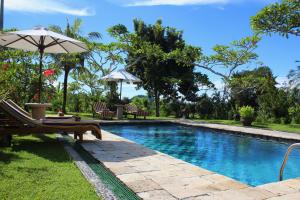 a swimming pool with a bench and an umbrella at Puri Bagus Manggis in Candidasa
