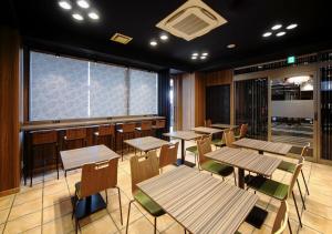 ein Restaurant mit Tischen und Stühlen und einem Fenster in der Unterkunft APA Hotel Hakata Ekimae 4 chome in Fukuoka
