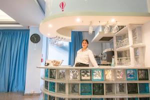 een vrouw achter een toonbank in een winkel bij Hotel Santiago in Rimini