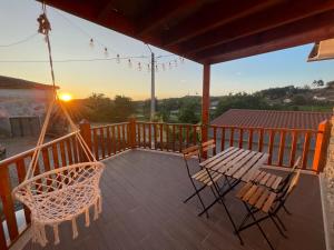 um alpendre com mesa e cadeiras e o pôr-do-sol em Casa do Souto - Nature & Experiences - Turismo Rural em Brangança