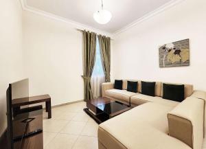 un soggiorno con divano e tavolo di RH - Spacious & bright 01BR, Near mall of Emirates a Dubai