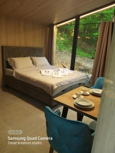 a bedroom with a bed and a table and a window at Apartman Košuta in Laktaši