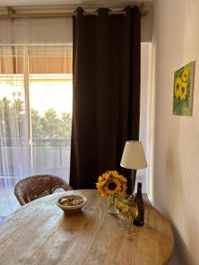 einen Holztisch mit einer Schüssel Sonnenblumen und Weingläsern in der Unterkunft Studio in the heart of Beaulieu sur mer in Beaulieu-sur-Mer