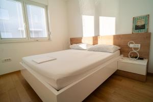 een groot wit bed in een kamer met 2 ramen bij Apartment Wing 77 by Belmont Realty in Zadar