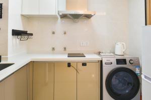 uma pequena cozinha com uma máquina de lavar roupa em Sea View Apartment with Washer Dryer Projector Refrigerator and Kitchen Shantou South High-Speed Railway St ation em Shantou