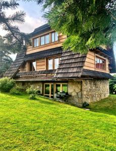 a house with a slate roof on a green lawn at Mountain cozy house in Tatras in Ząb
