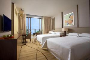 una camera d'albergo con due letti e una televisione di Sheraton Bailuhu Resort, Huizhou a Huizhou