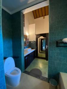 a blue bathroom with a toilet and a sink at Puri Ayu in Canggu