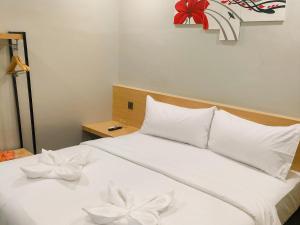 un letto con cuscini bianchi e un fiocco rosso sopra di Travel Biz Hotel Medan Mitra RedDoorz a Medan