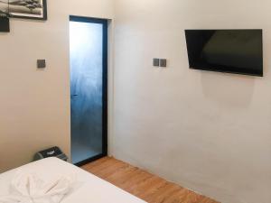 una camera con una porta con una televisione sul muro di Travel Biz Hotel Medan Mitra RedDoorz a Medan