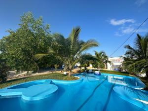 a large blue swimming pool with trees and palm trees at HOOM in Bwejuu