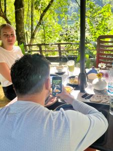 a man sitting at a table taking a picture with his cell phone at Moksha eco villa Ella in Ella