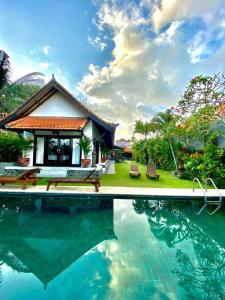 a villa with a pool in front of a house at Puri Ayu in Canggu