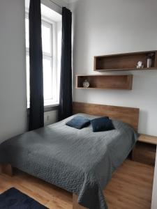 sypialnia z łóżkiem z niebieskimi poduszkami i oknem w obiekcie Apartament na Rynku w Gnieźnie w Gnieźnie
