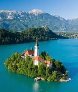 une île avec une église au milieu d'un lac dans l'établissement Apartments Karin, à Bled