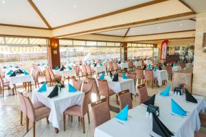 Oz Hotels Incekum Beach في ألانيا: مطعم بطاولات بيضاء وكراسي بمناديل زرقاء