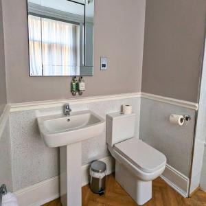 ein Badezimmer mit einem Waschbecken, einem WC und einem Spiegel in der Unterkunft Shaw Hill Hotel Golf And Country Club in Chorley