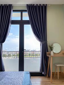 a bedroom with a large window with blue curtains at Homestay Sài Gòn in Phu Quoc